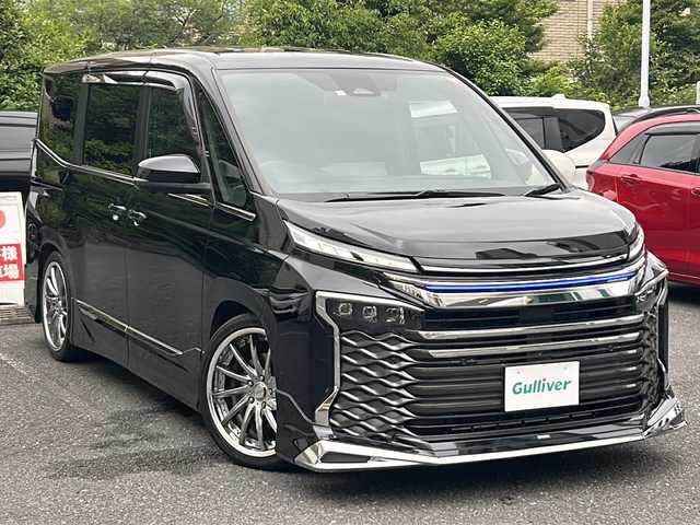 トヨタ ヴォクシー ハイブリッド S－Z 埼玉県 2023(令5)年 2.2万km アティチュードブラックマイカ 登録時21767km/ワンオーナー/モデリスタエアロ/両側パワースライドドア/パワーバックドア/ディスプレイオーディオ【コネクティッドナビ対応】Plus/   10.5インチ　車載ナビ/AM/FM/CD/DVD/BT//   USB/HDMI/フルセグTV/バックカメラ/全方位カメラ/純正フリップダウンモニター/ハーフレザーシート/シートヒーター（D+N席）/トヨタセーフティセンス/　プリクラッシュセーフティ/レーントレーシングアシスト/　レーンディパーチャーアラート/レーダークルーズコントロール/　アダプティブハイビームシステム/ロードサインアシスト/　ドライバー異常時対応システム/発進遅れ告知機能/　プロアクティブドライビングアシスト/緊急時操舵支援/　フロントクロストラフィックアラート/レーンチェンジアシスト/アドバンスパーク/アイドリングストップ/ドライブレコーダー/ETC2.0/デジタルインナーミラー/電動格納ミラー/ウィンカーミラー/プッシュスタート/スマートキーx2/純正LEDライト/オートライト/フォグランプ/社外19インチAW/ローダウン/ドアバイザー/純正フロアマット/保証書/取扱説明書