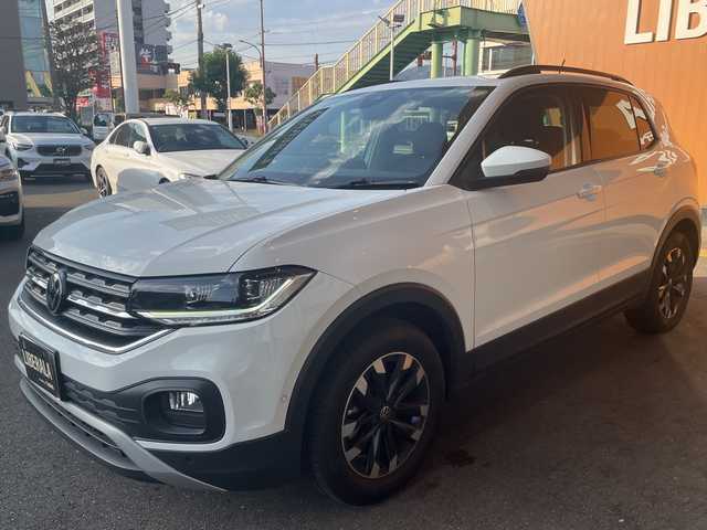 フォルクスワーゲン Ｔ－クロス TSI アクティブ 高知県 2022(令4)年 1.8万km 白 純正HDDナビ/【Bluetooth】/バックカメラ/クルーズコントロール(追従走行有り)/衝突被害軽減ブレーキ(プリクラッシュセーフティ：PCS)/パーキングアシスタント/ブラインドスポットモニター/横滑り防止/ルーフレール/コーナー、バックセンサー/ETC2.0/ドライブレコーダー前後/オートライト/純正LEDライト/スマートキー/プッシュスタート/MTモード付きAT/アイドリングストップ/純正アルミホイール 16インチ/ウインカーミラー/純正フロアマット