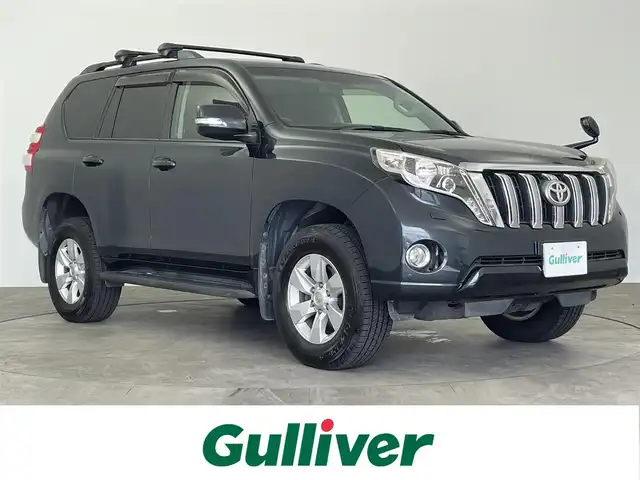 トヨタ ランドクルーザー プラド TX Lパッケージ 大分県 2016(平28)年 7.7万km ダークスチールマイカ 純正SDナビ　/（フルセグ/CD/DVD/Bluetooth）/フリップダウンモニター/レザーシート/パワーシート/シートヒーター/バックカメラ/クルーズコントロール/４WD/ETC/ステアリングスイッチ/7人乗り/電動格納ミラー/スマートキー・プッシュスタート/保証書・取扱説明書