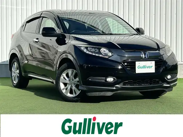 ホンダ ヴェゼル ハイブリッド X 香川県 2014(平26)年 2.1万km クリスタルブラックパール 登録時走行距離：20835km/純正7インチナビ/→CD再生/→Bluetooth/クルーズコントロール/革巻きステアリング/LEDヘッドライト/オートライト/純正16インチアルミホイール/プッシュスタート/純正フロアマット/電動格納ウィンカーミラー/バイザー