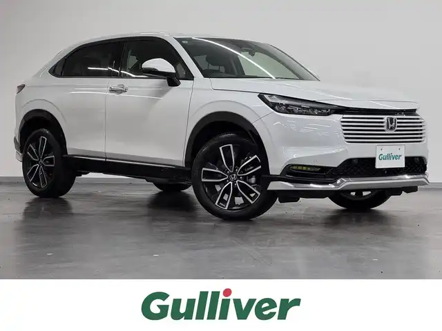 ホンダ ヴェゼル ハイブリッド e:HEV Z 三重県 2025(令7)年 1.1万km プラチナホワイトパール ハイブリッド/FF/MTモード付フロアCVT/純正 8インチ ディスプレイオーディオ VX-240ZFE/（FM/AM/USB/iPod/CarPlay/AndroidAuto/Bluetooth/HDMI）/バックカメラ/ドライブレコーダー 全方位＋後/ETC/純正 フロントロアースカート（Urban Style）/Honda SENSING/・衝突軽減ブレーキ/・先行車発進お知らせ機能/・路外逸脱抑制機能/・標識認識機能/・渋滞追従機能付アダプティブクルーズコントロール（ACC）/・車線維持支援システム（LKAS）/・トラフィックジャムアシスト（渋滞運転支援機能）/・ブラインドスポットインフォメーション/・誤発進抑制機能（前後）/・パーキングセンサーシステム/・アダプティブドライビングビーム/装備/・ハンズフリーアクセスパワーテールゲート（電動バックドア）/・ハーフレザーシート/・シートヒーター（D/N）/・ステアリングヒーター/・オートライトシステム/・LEDヘッドライト/・LEDフロントフォグランプ（黄）/・ヒルディセントコントロール/・左右独立オートエアコン/・自動防眩ルームミラー/・プッシュスタート/・純正18inAW/・スマートキーx1/など
