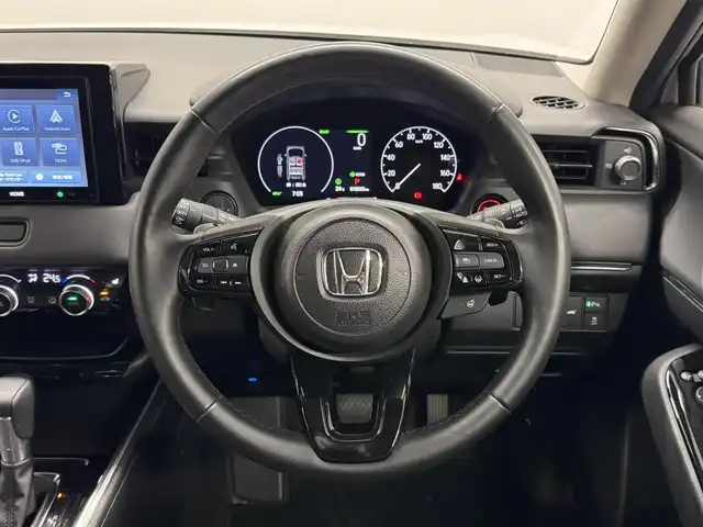 ホンダ ヴェゼル ハイブリッド e:HEV Z 三重県 2025(令7)年 1.1万km プラチナホワイトパール ハイブリッド/FF/MTモード付フロアCVT/純正 8インチ ディスプレイオーディオ VX-240ZFE/（FM/AM/USB/iPod/CarPlay/AndroidAuto/Bluetooth/HDMI）/バックカメラ/ドライブレコーダー 全方位＋後/ETC/純正 フロントロアースカート（Urban Style）/Honda SENSING/・衝突軽減ブレーキ/・先行車発進お知らせ機能/・路外逸脱抑制機能/・標識認識機能/・渋滞追従機能付アダプティブクルーズコントロール（ACC）/・車線維持支援システム（LKAS）/・トラフィックジャムアシスト（渋滞運転支援機能）/・ブラインドスポットインフォメーション/・誤発進抑制機能（前後）/・パーキングセンサーシステム/・アダプティブドライビングビーム/装備/・ハンズフリーアクセスパワーテールゲート（電動バックドア）/・ハーフレザーシート/・シートヒーター（D/N）/・ステアリングヒーター/・オートライトシステム/・LEDヘッドライト/・LEDフロントフォグランプ（黄）/・ヒルディセントコントロール/・左右独立オートエアコン/・自動防眩ルームミラー/・プッシュスタート/・純正18inAW/・スマートキーx1/など