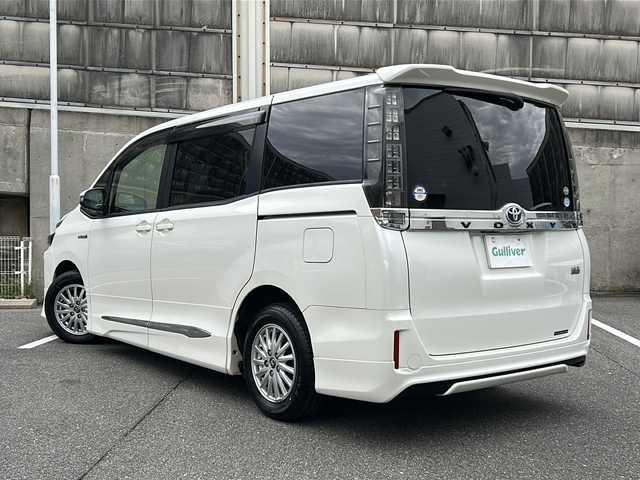 トヨタ ヴォクシー ハイブリッド V 愛知県 2015(平27)年 14.5万km ホワイトパールクリスタルシャイン ワンオーナー/置くだけ充電/モデリスタエアロ/革調シートカバー/純正SDナビ/フルセグTV・CD・DVD・SD・Bluetooth/バックカメラ/純正フリップダウンモニター/両側パワースライドドア/前席シートヒーター/LEDヘッドランプ/フォグランプ/ステアリングスイッチ/スマートキー/プッシュスタート/純正フロアマット/保証書/取扱説明書/スペアスマートキー