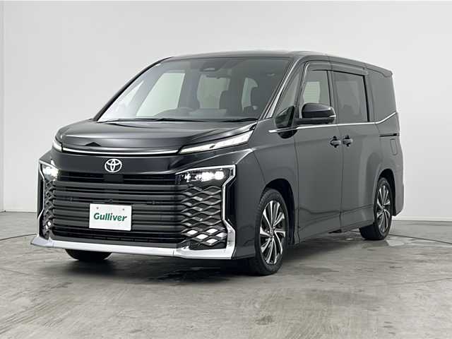 トヨタ ヴォクシー S－Z 三重県 2022(令4)年 2.1万km アティチュードブラックマイカ 禁煙車/純正ディスプレイオーディオ/・Bluetooth・フルセグ・CD/DVD・USB・HDMI/両側パワースライドドア/トヨタセーフティセンス/・プリクラッシュセーフティシステム/・レーンディパーチャーアラート/・レーダークルーズコントロール/・クリアランスソナー/・リアトラフィックアラート/・アドバンスドドライブ/・パーキングアシスト/.ブラインドスポットモニター/デジタルインナーミラー/ヘッドアップディスプレイ/アラウンドビューモニター/パワーバックドア/全席シートヒーター/ステアリングヒーター/スマートキー/プッシュスタート/スペアキー/純正フロアマット/純正１７インチアルミホイール/ビルドインETC2.0