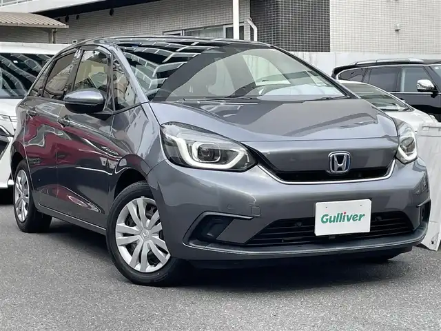ホンダ フィット e:HEVホーム 埼玉県 2021(令3)年 7万km シャイニンググレーM 登録時69378km/純正９インチナビ（BT/フルセグ）/バックカメラ/衝突軽減ブレーキ/路外逸脱制御機能/踏み間違い衝突軽減システム/レーダークルーズコントロール/パーキングセンサー/前後ドライブレコーダー/プッシュスタート/スマートキー×２/ビルトインETC/ハーフレザーシート/革巻きハンドル/ステアリングリモコン/オートライト/純正LEDヘッドライト/ウインカーミラー/横滑り防止装置/フロアマット/スタットレスタイヤ４本積込/保証書/取扱説明書/ナビ取扱説明書