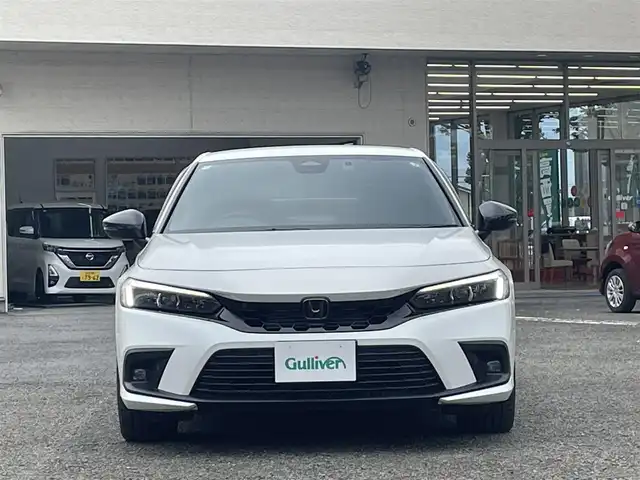 ホンダ シビック e:HEV 宮城県 2024(令6)年 1.5万km プラチナホワイトパール 純正リアスポイラー/純正ディスプレイオーディオナビ/フルセグＴＶ/BT/USB/AM/FM/スマートフォン連携/ホンダセンシング/・衝突軽減ブレーキ（CMBS）/・踏み間違い衝突軽減システム/・路外逸脱抑制機能/・歩行者事故低減ステアリング/・先行車発信お知らせ機能/・標識認識機能/・アダプティブドライビングビーム/・ブラインドスポットインフォメーション/・後退出庫サポート/・パーキングセンサーシステム/・ドライバー注意力モニター/・車線維持支援システム（LKAS）/ハーフレザーシート/D/N席パワーシート/シートヒーター/ワイヤレス充電/純正ドライブレコーダー（前後）/ビルトインＥＴＣ2.0/パドルシフト/電動パーキングブレーキ/オートブレーキホールド/カーテンエアバッグ/プッシュスタート/スマートキー×2/保証書/取扱説明書