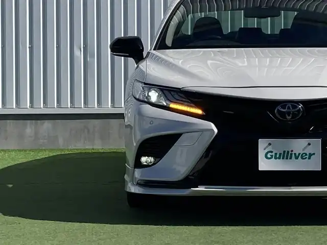 トヨタ カムリ WSレザーパッケージ 香川県 2020(令2)年 8.3万km プラチナホワイトパールマイカ 登録時走行距離：82489km/TRDエアロ/→フロントスポイラー/→サイドスカート/→リヤバンパースポイラー/トヨタセーフティーセンス/→プリクラッシュセーフティ/→レーンディパーチャーアラート/→レーダークルーズコントロール/→クリアランスソナー/→ヘッドアップディスプレイ/純正9インチディスプレイオーディオ/→ナビ機能あり/→フルセグTV・BT/ブラックレザーシート/シートヒーター/パワーシート/革巻きステアリング/ステアリングリモコン/パドルシフト/MTモード付AT/ホールド機能付き電子パーキングブレーキ/LEDヘッドライト/LEDフォグライト/純正18インチAW/スマートキー/プッシュスタート
