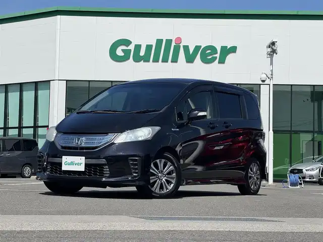 ホンダ フリード ハイブリット ジャストセレクション 愛媛県 2013(平25)年 8.4万km プレミアムブラキッシュパール 登録時走行距離：83666Km/純正HDDナビ/AM/FM/ワンセグTV/ＤＶＤ/ETC/ＡＡＣ/Bカメラ/クルーズコントロール/両側パワスラ/横滑り防止装置/盗難防止装置/ハーフレザーシート/キセノンヘッドライト/オートライト/リモコンキー/スペアキー1本/純正アルミホイール/純正フロアマット
