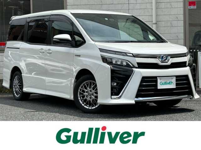トヨタ ヴォクシー ハイブリッド ZS 福岡県 2017(平29)年 9.3万km ホワイトパールクリスタルシャイン ワンオーナー/エアロ（サイド）/純正10インチメモリナビ【NSZN-Z66T】/　（AM/FM/HDMI/Bluetooth/フルセグTV）/バックカメラ/純正12インチフリップダウンモニター　リモコン付き【V12T-R66C】/トヨタセーフティーセンス/・プリクラッシュセーフティー/・レーントレーシングサポート/・レーンディパーチャーアラート/・クルーズコントロール/・オートマチックハイビーム/・車両接近通報装置/・横滑り防止装置/・先行者発進アラーム/両側パワースライドドア/純正16インチアルミホイール/シートヒーター/黒色レザー調シートカバー/ビルトインETC/オートライト/フロントフォグランプ/盗難防止装置/電格ミラー/ドアバイザー/プッシュスタート/純正フロアマット/ISOFIX/2.1A電源プラグ×2/スペアキー×1/保証書/取扱説明書/ナビ取扱説明書