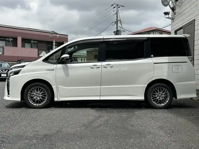 トヨタ ヴォクシー ハイブリッド ZS 福岡県 2017(平29)年 9.3万km ホワイトパールクリスタルシャイン ワンオーナー/エアロ（サイド）/純正10インチメモリナビ【NSZN-Z66T】/　（AM/FM/HDMI/Bluetooth/フルセグTV）/バックカメラ/純正12インチフリップダウンモニター　リモコン付き【V12T-R66C】/トヨタセーフティーセンス/・プリクラッシュセーフティー/・レーントレーシングサポート/・レーンディパーチャーアラート/・クルーズコントロール/・オートマチックハイビーム/・車両接近通報装置/・横滑り防止装置/・先行者発進アラーム/両側パワースライドドア/純正16インチアルミホイール/シートヒーター/黒色レザー調シートカバー/ビルトインETC/オートライト/フロントフォグランプ/盗難防止装置/電格ミラー/ドアバイザー/プッシュスタート/純正フロアマット/ISOFIX/2.1A電源プラグ×2/スペアキー×1/保証書/取扱説明書/ナビ取扱説明書