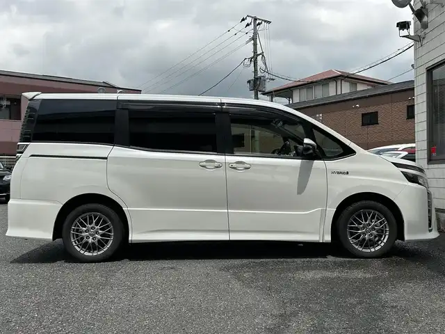 トヨタ ヴォクシー ハイブリッド ZS 福岡県 2017(平29)年 9.3万km ホワイトパールクリスタルシャイン ワンオーナー/エアロ（サイド）/純正10インチメモリナビ【NSZN-Z66T】/　（AM/FM/HDMI/Bluetooth/フルセグTV）/バックカメラ/純正12インチフリップダウンモニター　リモコン付き【V12T-R66C】/トヨタセーフティーセンス/・プリクラッシュセーフティー/・レーントレーシングサポート/・レーンディパーチャーアラート/・クルーズコントロール/・オートマチックハイビーム/・車両接近通報装置/・横滑り防止装置/・先行者発進アラーム/両側パワースライドドア/純正16インチアルミホイール/シートヒーター/黒色レザー調シートカバー/ビルトインETC/オートライト/フロントフォグランプ/盗難防止装置/電格ミラー/ドアバイザー/プッシュスタート/純正フロアマット/ISOFIX/2.1A電源プラグ×2/スペアキー×1/保証書/取扱説明書/ナビ取扱説明書