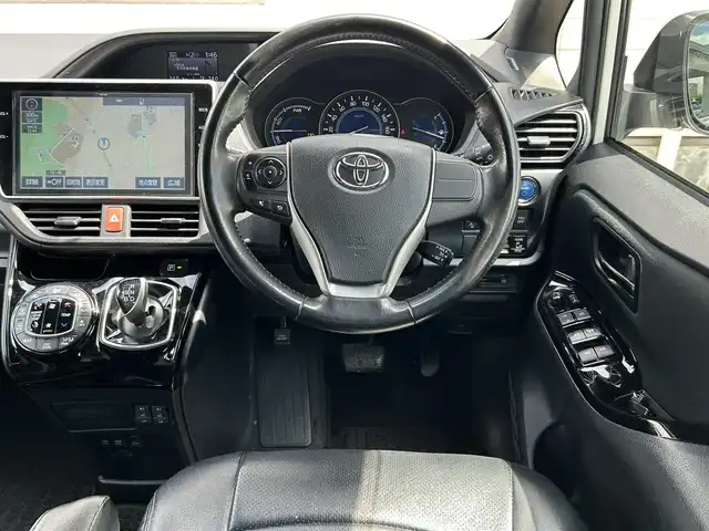 トヨタ ヴォクシー ハイブリッド ZS 福岡県 2017(平29)年 9.3万km ホワイトパールクリスタルシャイン ワンオーナー/エアロ（サイド）/純正10インチメモリナビ【NSZN-Z66T】/　（AM/FM/HDMI/Bluetooth/フルセグTV）/バックカメラ/純正12インチフリップダウンモニター　リモコン付き【V12T-R66C】/トヨタセーフティーセンス/・プリクラッシュセーフティー/・レーントレーシングサポート/・レーンディパーチャーアラート/・クルーズコントロール/・オートマチックハイビーム/・車両接近通報装置/・横滑り防止装置/・先行者発進アラーム/両側パワースライドドア/純正16インチアルミホイール/シートヒーター/黒色レザー調シートカバー/ビルトインETC/オートライト/フロントフォグランプ/盗難防止装置/電格ミラー/ドアバイザー/プッシュスタート/純正フロアマット/ISOFIX/2.1A電源プラグ×2/スペアキー×1/保証書/取扱説明書/ナビ取扱説明書