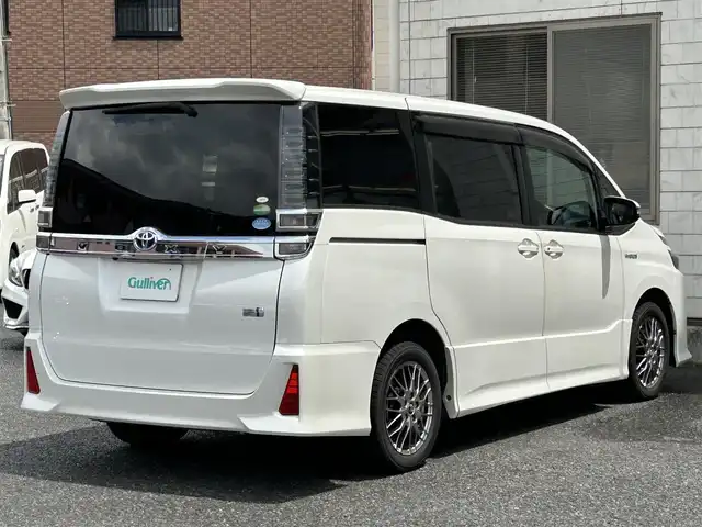 トヨタ ヴォクシー ハイブリッド ZS 福岡県 2017(平29)年 9.3万km ホワイトパールクリスタルシャイン ワンオーナー/エアロ（サイド）/純正10インチメモリナビ【NSZN-Z66T】/　（AM/FM/HDMI/Bluetooth/フルセグTV）/バックカメラ/純正12インチフリップダウンモニター　リモコン付き【V12T-R66C】/トヨタセーフティーセンス/・プリクラッシュセーフティー/・レーントレーシングサポート/・レーンディパーチャーアラート/・クルーズコントロール/・オートマチックハイビーム/・車両接近通報装置/・横滑り防止装置/・先行者発進アラーム/両側パワースライドドア/純正16インチアルミホイール/シートヒーター/黒色レザー調シートカバー/ビルトインETC/オートライト/フロントフォグランプ/盗難防止装置/電格ミラー/ドアバイザー/プッシュスタート/純正フロアマット/ISOFIX/2.1A電源プラグ×2/スペアキー×1/保証書/取扱説明書/ナビ取扱説明書