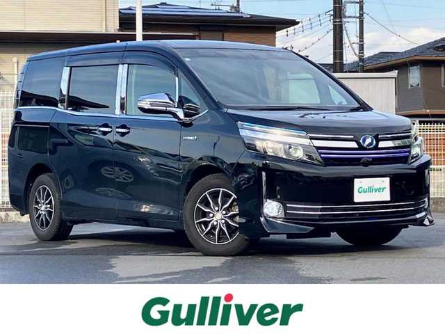 トヨタ ヴォクシー ハイブリッド V 静岡県 2014(平26)年 11.8万km ブラック エンジンスタートボタン/パワーステアリング/パワーウィンドウ/アイドリングストップ/スマートキー/Wオートエアコン/クルーズコントロール/ALPINE製11インチナビ（CD/DVD/BT/フルセグ）/ALPINE製10.2インチ後席モニター/バックカメラ/フロアマット/三列シート/ウォークスルー/D席N席シートヒーター/布シート/両側パワースライドドア/社外アルミホイール/ABS/オートライト/W+サイドエアバッグ/カーテンエアバッグ/衝突軽減システム