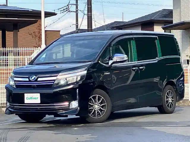 トヨタ ヴォクシー ハイブリッド V 静岡県 2014(平26)年 11.8万km ブラック エンジンスタートボタン/パワーステアリング/パワーウィンドウ/アイドリングストップ/スマートキー/Wオートエアコン/クルーズコントロール/ALPINE製11インチナビ（CD/DVD/BT/フルセグ）/ALPINE製10.2インチ後席モニター/バックカメラ/フロアマット/三列シート/ウォークスルー/D席N席シートヒーター/布シート/両側パワースライドドア/社外アルミホイール/ABS/オートライト/W+サイドエアバッグ/カーテンエアバッグ/衝突軽減システム