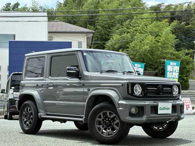 スズキ ジムニー シエラ JC 熊本県 2021(令3)年 1.7万km ミディアムグレー ダムドリトルGスタンダード/・フロントグリル（エンブレムスズキ）/・フロントバンパー/・オーバーフェンダー＆アルミサイドモール/・スペアタイヤカバー/・G15エンブレム/社外10V型有機ELディスプレイナビ（CN-F1X10LD）/【フルセグTV/Bluetooth再生/CD/DVD】/バックカメラ/デュアルセンサーブレーキサポート/車線逸脱警報システム/クルーズコントロール/レザー調シートカバー/シートヒーター/革巻きステアリング/ステアリングスイッチ/LEDオートライト/フォグライト/ETC/保証書/取扱説明書