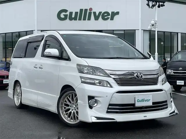 トヨタ ヴェルファイア 2．4Z Gエディション 長崎県 2013(平25)年 9.6万km パール 純正メモリナビ/CD/DVD/BT/フルセグTV/バックカメラ/純正フリップダウンモニター/両側パワースライドドア/クルーズコントロール/革調シートカバー/前席パワーシート/D席メモリーシート/モデリスタエアロ/パワーバックドア/ドライブレコーダー前後/社外レーダー/室内灯LEDヘッドライト/LEDヘッドライト/純正AW積み込み