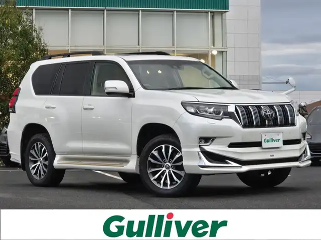 トヨタ ランドクルーザー プラド TX Lパッケージ 鹿児島県 2018(平30)年 5万km ホワイトパールクリスタルシャイン 前後モデリスタエアロ　/ムーンルーフ　/ヒッチメンバー　/ヒッチキャリア　/ラゲージプロテクター　/ＡＬＰＩＮＥナビ　/ウッドコンビステア　/純正サイドステップカバー　/ルーフレール　/純正アルミホイール（１９インチ）/前後コーナーセンサー/Bluetoothオーディオ/フルセグテレビ/D+N席シートヒーター/D+N席シートベンチレーション/D+N席パワーシート/電動格納サードシート/社外フロアマット/プッシュスタート/スマートキー/横滑り防止装置/レーンキープアシスト