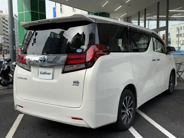 トヨタ アルファードハイブリット G 広島県 2015(平27)年 7.8万km ラグジュアリーホワイトパールクリスタルシャインガラスフレーク ワンオーナー/純正メーカーオプション9.2インチSDナビ/・JBLサウンドシステム/・フルセグTV/・Bluetooth/パノラミックビューモニター/レーダークルーズコントロール/インテリジェントクリアランスソナー/プリクラッシュセーフティシステム/モデリスタエアロ/ツインムーンルーフ/両側パワースライドドア/パワーシート（D/N）/N席パワーオットマン/スマートキープッシュスタート