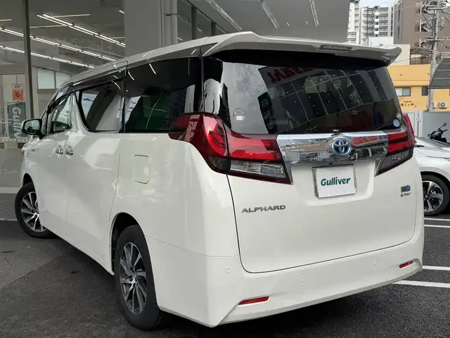 トヨタ アルファードハイブリット G 広島県 2015(平27)年 7.8万km ラグジュアリーホワイトパールクリスタルシャインガラスフレーク ワンオーナー/純正メーカーオプション9.2インチSDナビ/・JBLサウンドシステム/・フルセグTV/・Bluetooth/パノラミックビューモニター/レーダークルーズコントロール/インテリジェントクリアランスソナー/プリクラッシュセーフティシステム/モデリスタエアロ/ツインムーンルーフ/両側パワースライドドア/パワーシート（D/N）/N席パワーオットマン/スマートキープッシュスタート