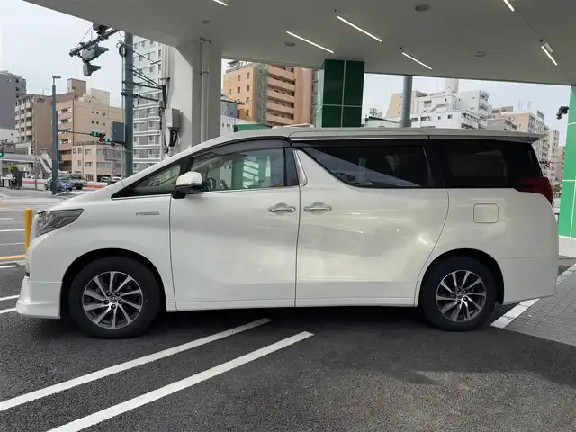 トヨタ アルファードハイブリット G 広島県 2015(平27)年 7.8万km ラグジュアリーホワイトパールクリスタルシャインガラスフレーク ワンオーナー/純正メーカーオプション9.2インチSDナビ/・JBLサウンドシステム/・フルセグTV/・Bluetooth/パノラミックビューモニター/レーダークルーズコントロール/インテリジェントクリアランスソナー/プリクラッシュセーフティシステム/モデリスタエアロ/ツインムーンルーフ/両側パワースライドドア/パワーシート（D/N）/N席パワーオットマン/スマートキープッシュスタート
