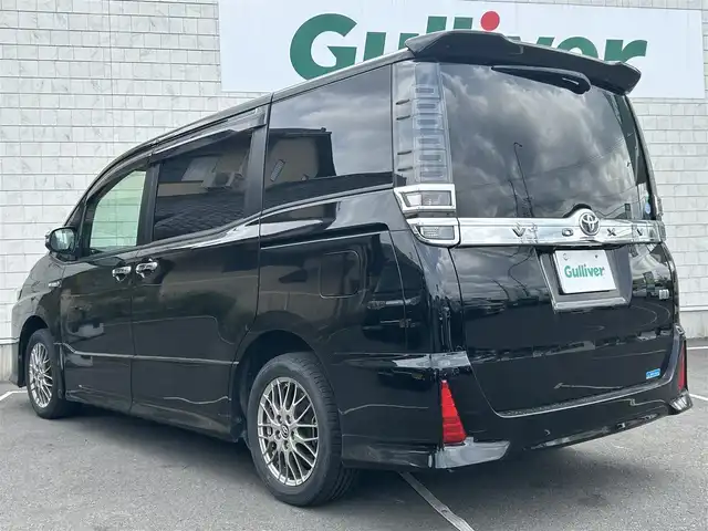 トヨタ ヴォクシー ハイブリッド ZS 煌 福岡県 2018(平30)年 7.7万km ブラック 社外９型ナビ/（AM/FM/CD/DVD/BT)/フルセグTV/バックカメラ/両側パワースライドドア /純正フリップダウンモニター/クルーズコントロール/ビルトインETC/スマートキー/プッシュスタート/前席シートヒーター /プリクラッシュ セーフティ/レーンキープアシスト/横滑り防止装置/純正１６インチAW/LEDヘッドライト/フロアマット/取り扱い説明書/保証書