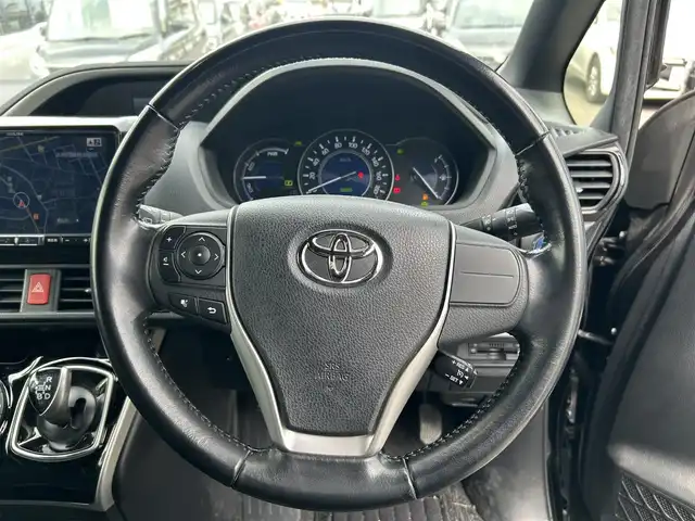 トヨタ ヴォクシー ハイブリッド ZS 煌 福岡県 2018(平30)年 7.7万km ブラック 社外９型ナビ/（AM/FM/CD/DVD/BT)/フルセグTV/バックカメラ/両側パワースライドドア /純正フリップダウンモニター/クルーズコントロール/ビルトインETC/スマートキー/プッシュスタート/前席シートヒーター /プリクラッシュ セーフティ/レーンキープアシスト/横滑り防止装置/純正１６インチAW/LEDヘッドライト/フロアマット/取り扱い説明書/保証書