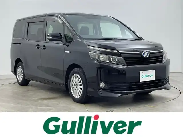 トヨタ ヴォクシー ハイブリッド V 岡山県 2015(平27)年 7.6万km ブラック 純正9インチナビ/型番:NSZT-Y64T/【Bluetooth/フルセグTV/CD/DVD】/11インチ後席モニター/型番:V11T-R62C/両側パワースライドドア/バックカメラ/前席シートヒーター/置くだけ充電/ビルトインETC/LEDヘッドライト/オートライト/フォグランプ/純正フロアマット/純正15インチアルミホイール/プッシュスタート/スマートキー×1