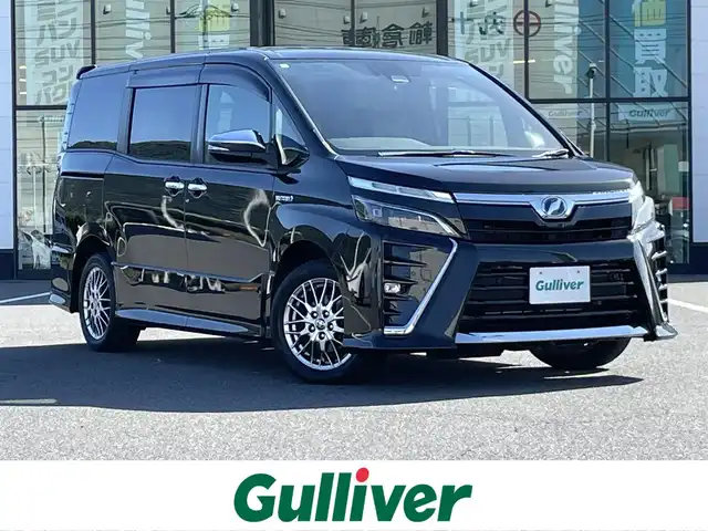 トヨタ ヴォクシー ハイブリッド ZS 煌Ⅱ 岡山県 2019(令1)年 9.9万km イナズマスパーキングブラックガラスフレーク 登録時走行距離　98242km/禁煙車/純正10インチナビ(型番:NSZN-Z68T)/　(CD/DVD/フルセグTV/Bluetooth)/バックカメラ/クルーズコントロール/衝突被害軽減システム/車線逸脱警報（レーンキープアシスト）/コーナーセンサー/両側パワースライドドア/シートヒーター(D・N席)/革巻きステアリング/ステアリングスイッチ/純正LEDヘッドライト/フォグライト/オートライト/プッシュスタート/スマートキー/アイドリングストップ/純正アルミホイール 16インチ/ドアバイザー/ウインカーミラー/電動格納ミラー/オートリトラミラー/純正フロアマット/横滑防止装置/盗難防止装置
