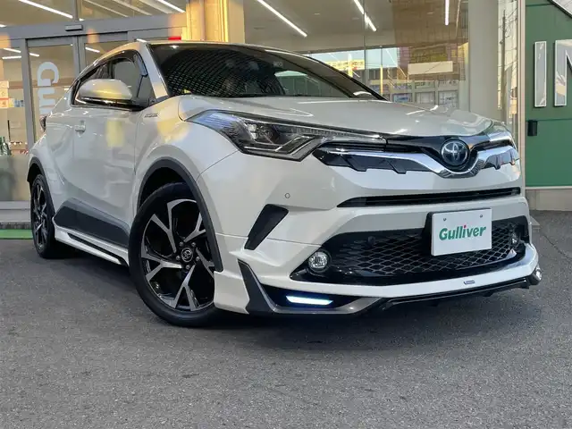 トヨタ Ｃ－ＨＲ G 高知県 2018(平30)年 6.8万km ホワイトパールクリスタルシャイン 登録時走行距離６７１０４ｋｍ/モデリスタエアロ/社外９インチメモリーナビ/　【DVD/Bluetooth/CD/SD/AM/FM】/フルセグTV/バックカメラ/ステアリングスイッチ/ハーフレザーシート/前席シートヒーター/Toyota Sefety Sense/　・プリクラッシュセーフティシステム/　・レーンディパーチャーアラート/　・オートマチックハイビーム/　・レーダークルーズコントロール/LEDヘッドライト/LEDフォグライト/オートライト/プッシュスタート/スマートキー/スペアキー/電動パーキング/ブレーキホールド/前後ドライブレコーダー/ビルトインETC/純正フロアマット/ドアバイザー/整備記録簿/取扱説明書