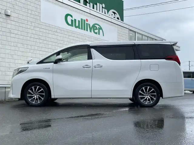 トヨタ アルファードハイブリット G 山形県 2016(平28)年 7.6万km ホワイトパールクリスタルシャイン 禁煙車/4WD/純正10インチナビ//フルセグ/CD/DVD/SD/AM//FM/iPod/BT/AUX/純正フリップダウンモニター/ハーフレザーシート/ETC/クルーズコントロール/プリクラッシュセーフティー/ステアリングスイッチ/オートLEDヘッドライト/オートワイパー/フォグランプ/プッシュスタート