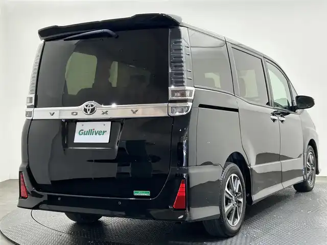 トヨタ ヴォクシー ZS 煌Ⅲ 愛媛県 2021(令3)年 2.6万km ブラック ・１０型ナビ（フルセグＴＶ・ＢＴ・ＣＤ・ＤＶＤ・ＳＤ・ＦＭ・ＡＭ）/・バックカメラ　/・１２．１型後席モニター　/・クルーズコントロール　/・ＥＴＣ　/・衝突軽減ブレーキ　/・オートマチックハイビーム　/・レーンキープアシスト/・両側パワースライドドア/・USB充電