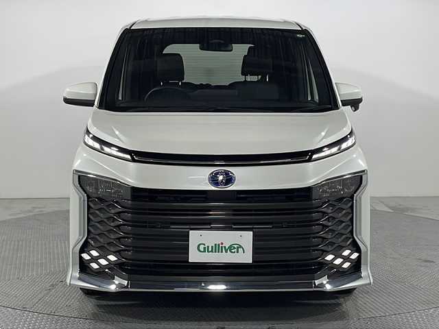トヨタ ヴォクシー ハイブリッド S－Z 広島県 2023(令5)年 0.4万km ホワイトパールクリスタルシャイン 純正10.5型ディスプレイオーディオ（メモリナビ/　AppleCarPlay/AndroidAuto/フルセグTV）/快適利便パッケージ/・ハンズフリーデュアルパワースライドドア/・パワーバックドア/・ステアリングヒーター/・2列目キャプテンシート（オットマン/シートヒーター）/バックカメラ/前席シートヒーター/セーフティセンス/・プリクラッシュセーフティ/・レーントレーシングアシスト/・レーンディパーチャーアラート/・オートマチックハイビーム/・レーダークルーズコントロール/・プロアクティブドライビングアシスト/CD/DVDデッキ/ETC2.0/USB/HDMI入力端子/AC100V/1500W電源