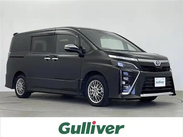 トヨタ ヴォクシー ハイブリッド ZS 煌Ⅲ 鹿児島県 2021(令3)年 7.6万km イナズマスパーキングブラックガラスフレーク 純正ナビ/（CD/DVD/BT/フルセグTV）/プリクラッシュセーフティ/レーンキープアシスト/クルーズコントロール/純正フリップダウンモニター/両側パワースライドドア/ハーフレザーシート/シートヒーター/オートライト/オートマチックハイビーム/純正アルミホイール/純正フロアマット/純正ドアバイザー/コーナーセンサ―