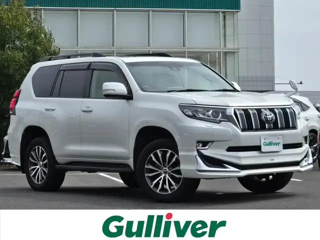 トヨタ ランドクルーザー プラド TX Lパッケージ 鹿児島県 2019(平31)年 6.7万km ホワイトパールクリスタルシャイン ムーンルーフ　/モデリスタエアロ（リア／フロント）　/ルーフレール　/ＡＬＰＩＮＥナビ　/Ｂｌｕｅｔｏｏｔｈオーディオ　/バックカメラ　/Ｄ＋Ｎ席シートヒーター　/Ｄ＋Ｎ席シートベンチレーション/D+N席パワーシート　/ビルトインＥＴＣ/前方ドライブレコーダー/前後コーナーセンサー/レーダークルーズコントロール/純正アルミホイール(19インチ)/横滑り防止装置/レーンキープアシスト/プッシュスタート/スマートキー/エアバッグ(W+サイド)/カーテンエアバッグ