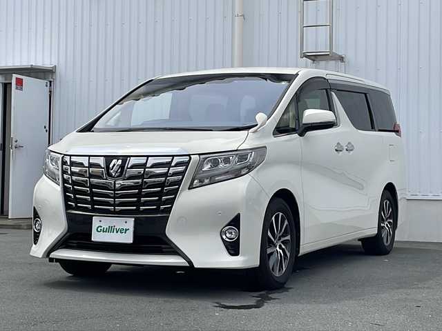 トヨタ アルファード G 三重県 2015(平27)年 5.7万km ラグジュアリーホワイトパールクリスタルシャインガラスフレーク プッシュスタート/電動格納ミラー/両側パワースライドドア/ビルトインETC/横滑り防止/レーダークルーズコントロール/パワーシート{D+N席）/オットマン/ステアリングスイッチ/革巻きステアリング/オートライト/前後ドライブレコーダー/後席フリップダウンモニター/電動パーキング/純正フロアマット/純正9型ナビ（AM/FM/CD/DVD/TV/BT）/フルセグTV/コーナーセンサー/パワーバックドア/スペアキー/リアサンシェード/LEDヘッドライト