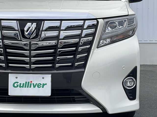 トヨタ アルファード G 三重県 2015(平27)年 5.7万km ラグジュアリーホワイトパールクリスタルシャインガラスフレーク プッシュスタート/電動格納ミラー/両側パワースライドドア/ビルトインETC/横滑り防止/レーダークルーズコントロール/パワーシート{D+N席）/オットマン/ステアリングスイッチ/革巻きステアリング/オートライト/前後ドライブレコーダー/後席フリップダウンモニター/電動パーキング/純正フロアマット/純正9型ナビ（AM/FM/CD/DVD/TV/BT）/フルセグTV/コーナーセンサー/パワーバックドア/スペアキー/リアサンシェード/LEDヘッドライト