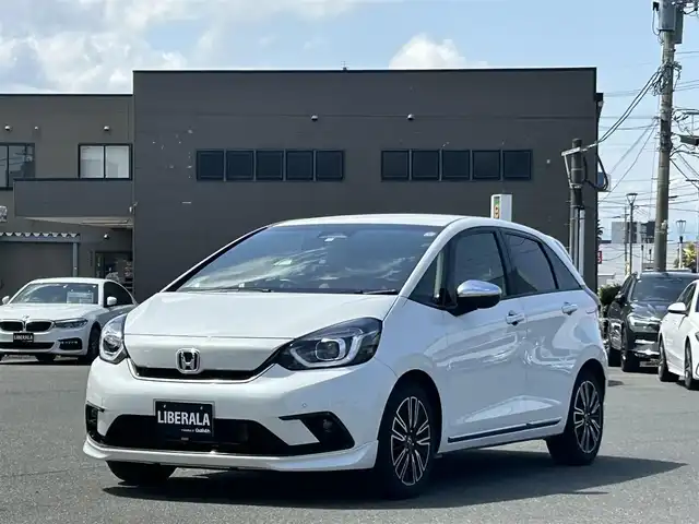 ホンダ フィット e:HEVリュクス 福岡県 2020(令2)年 4.8万km プラチナホワイトパール 社外ナビ(MDV-M906HD)/CD/DVD/SD/BT/フルセグ/ETC/バックカメラ/置くだけ充電/オートホールド/ホンダセンシング/レーンキープアシスト/革巻きステアリング/ステアリングスイッチ/ハーフレザーシート/シートヒーターD-N/LEDヘッドライト/オートライト/オートハイビーム/フォグライト前/コーナーセンサー前後/純正フロアマット/純正16AW