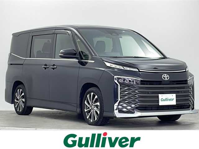 トヨタ ヴォクシー S－Z 大阪府 2022(令4)年 2.5万km グリッターブラックガラスフレーク 純正10.5インチディスプレイオーディオ/【ナビ/BT/フルセグTV/USB/DVD/HDMI]/バックカメラ/ETC2.0/ドライブレコーダー前後　TZ-DR210/快適利便パッケージ/・オットマン/・パワーバックドア/・ハンズフリーデュアルパワースライドドア/・ナイノーX/・ステアリングヒーター/・二列目シートヒーター/両側パワースライドドア/衝突被害軽減システム/ブラインドスポットモニター/クルーズコントロール追従/コーナーセンサー前後/オートライト/サンシェード/ハーフレザーシート/純正17インチAW/ワンオーナ/スペアキー